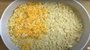 Creamy macaroni and cheese in a dish, topped with shredded cheddar, ready to serve or bake.